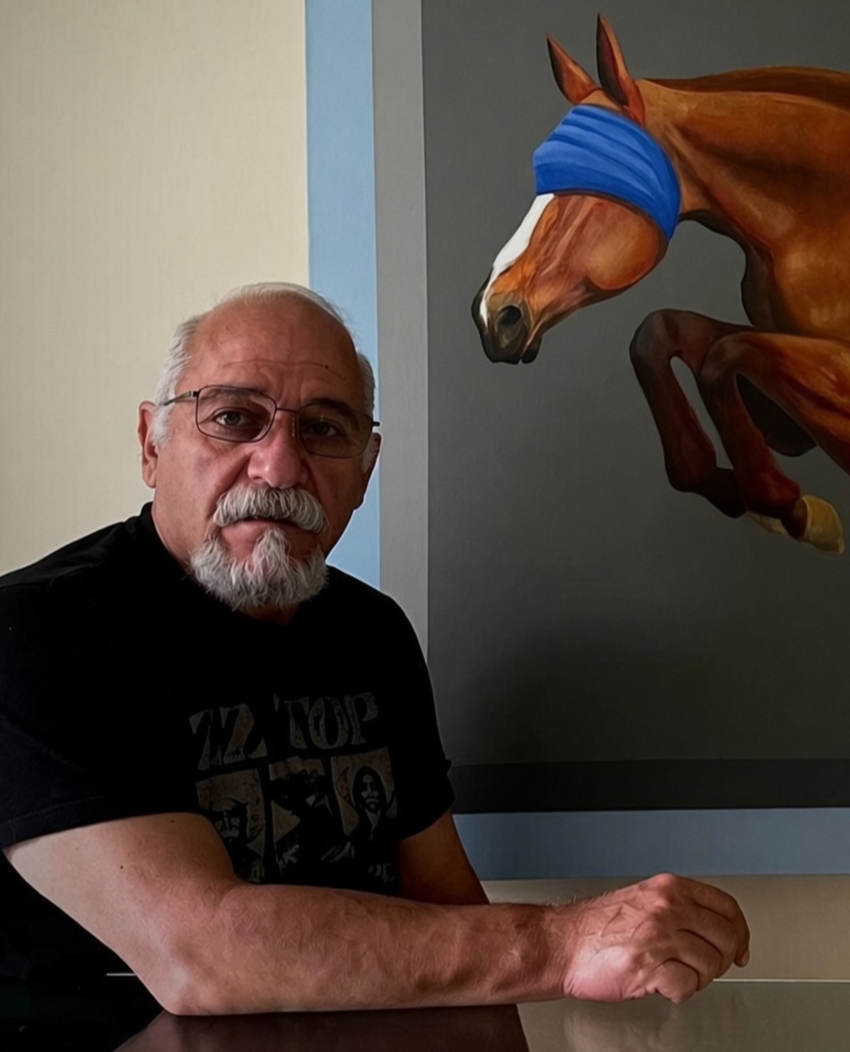 Fuad Hamdi seated beside an artwork